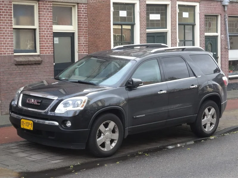 Black GMC Acadia parked on a sidewalk