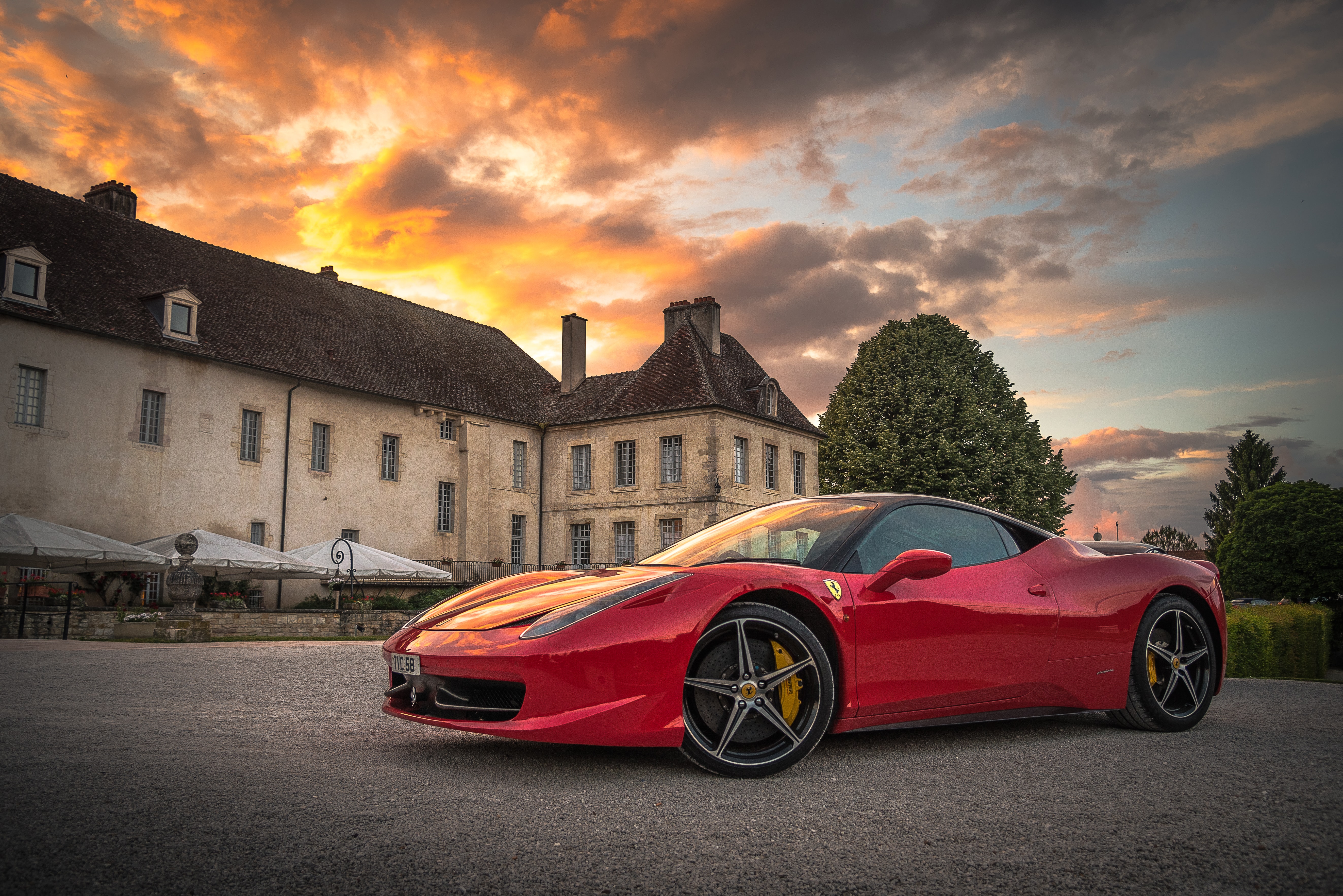 red sports car in front of a mansion