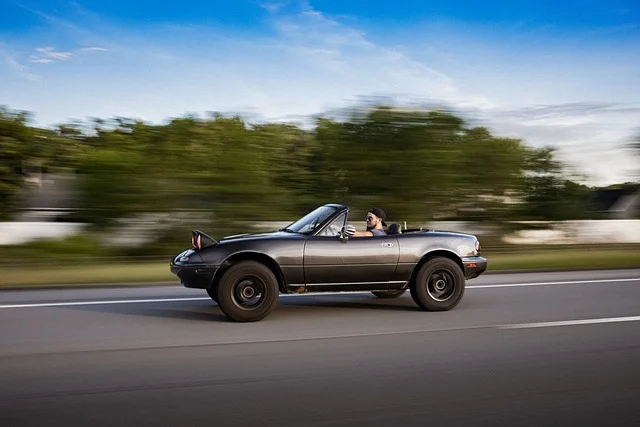 Mazda Miata driving quickly down a street