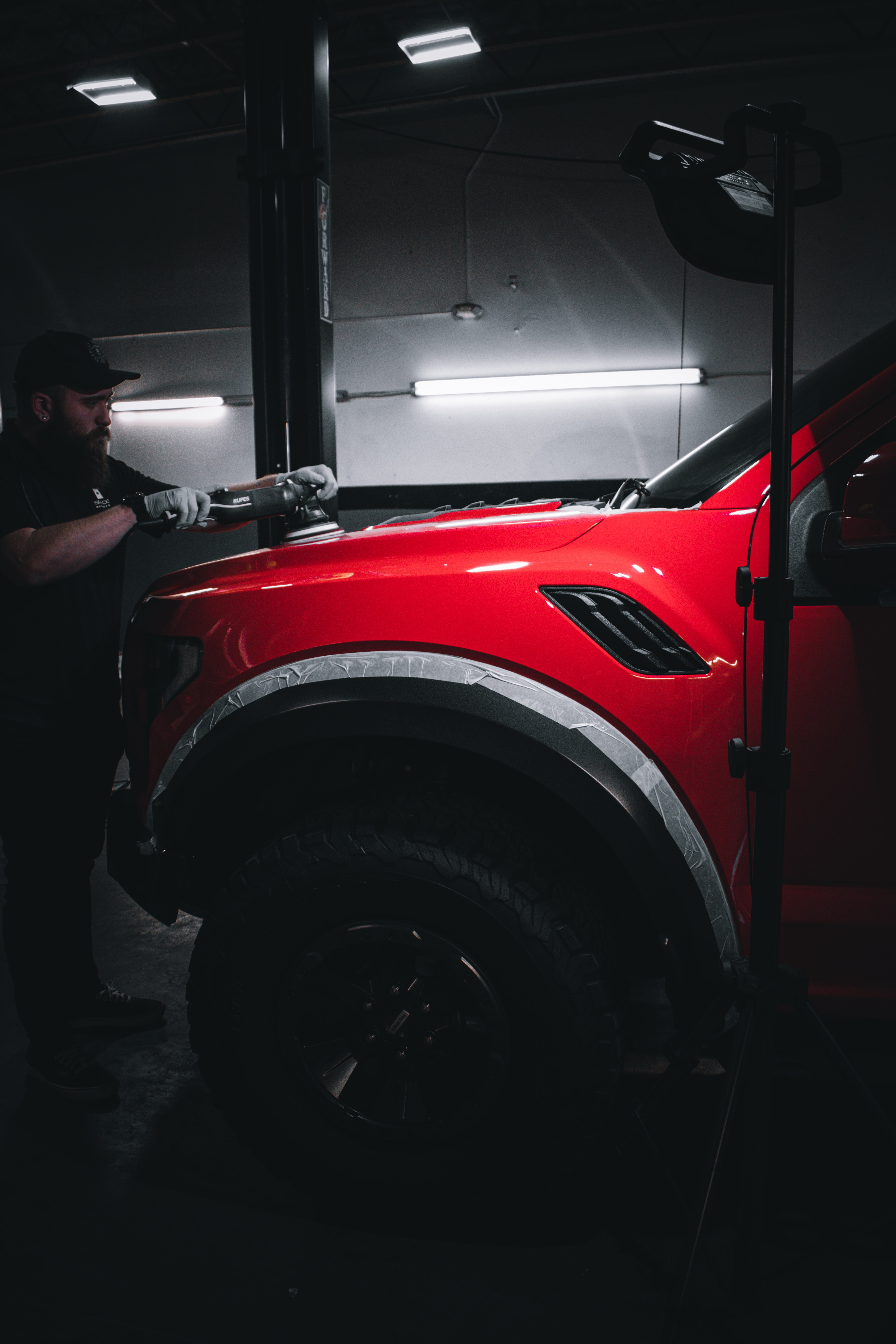 man finishing a red paint job on a car